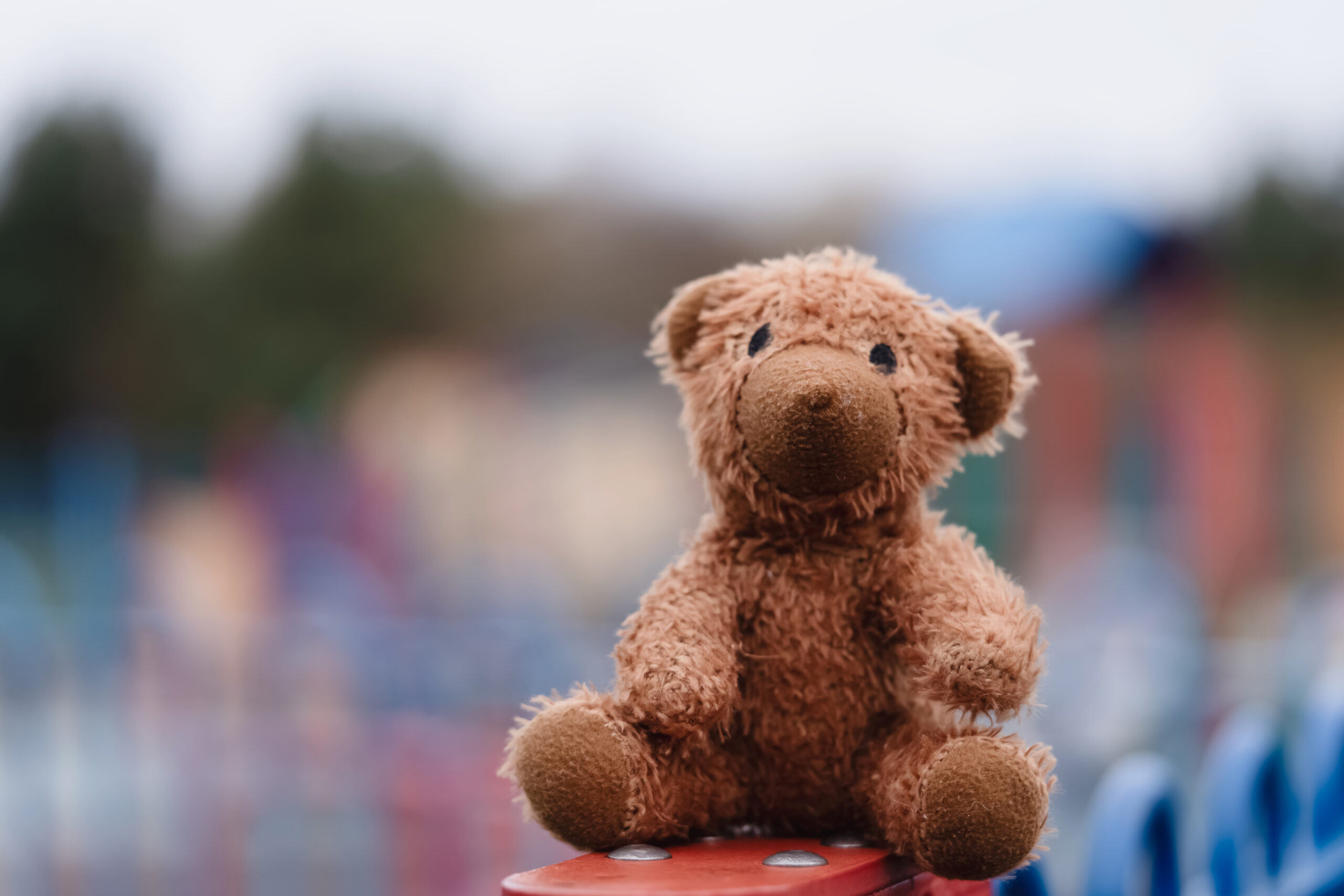 lost teddy bear toy sitting on fence in playground 2024 07 03 04 10 42 utc scaled